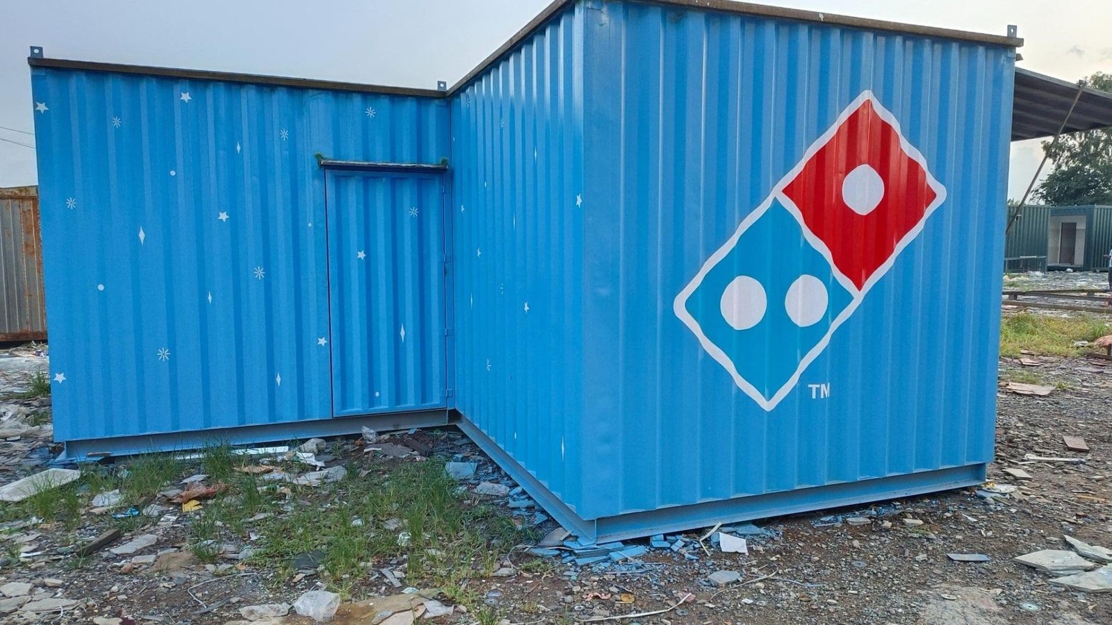 Porta cabin in a construction site with Domino's logo, featuring bright blue colors