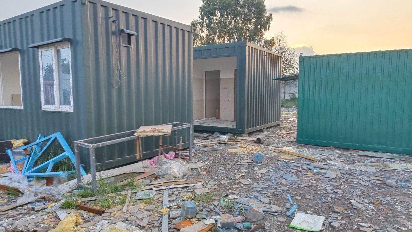Green portable cabins in a cluttered construction area