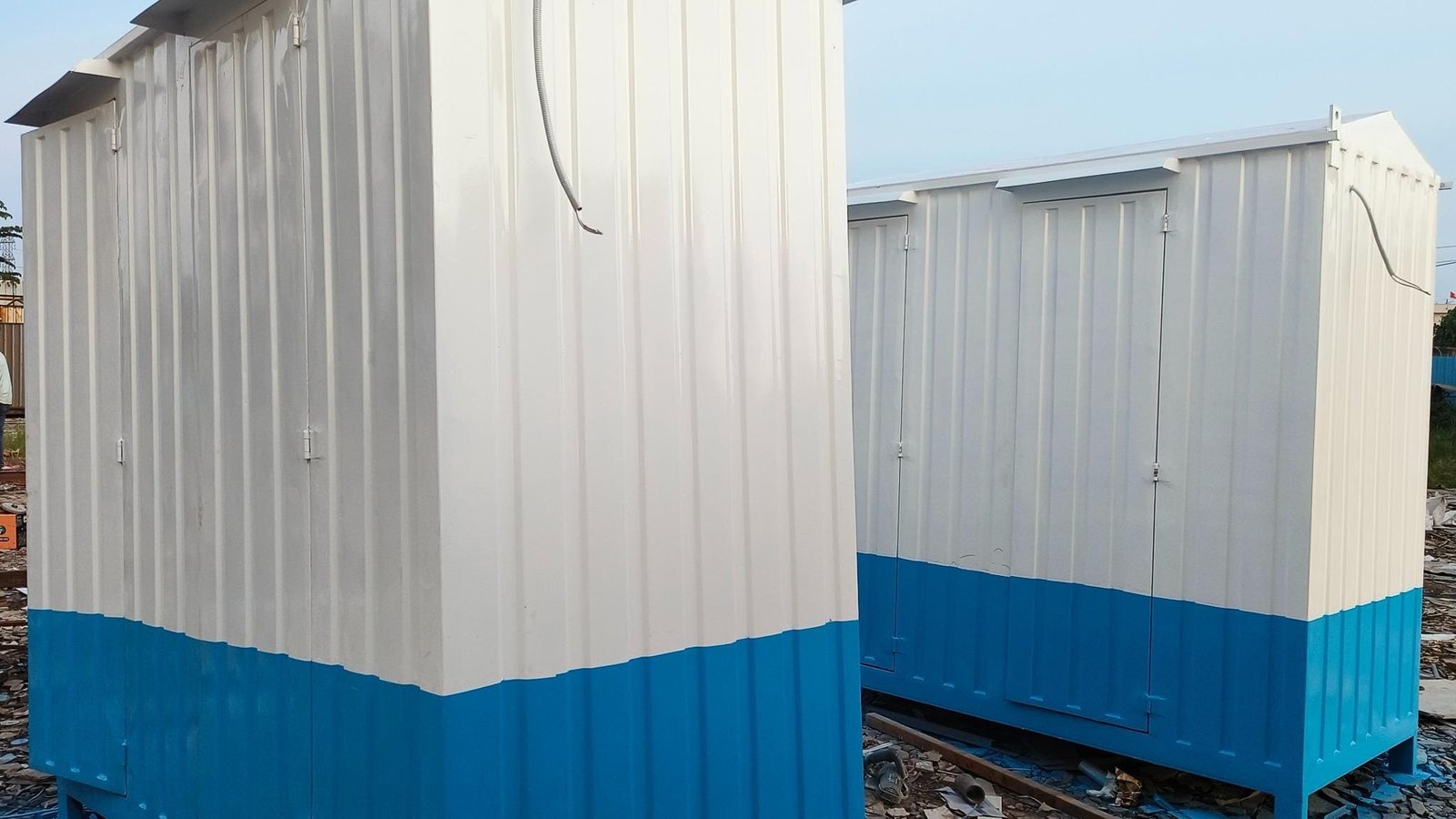 Two white and blue portable cabins on a construction site.