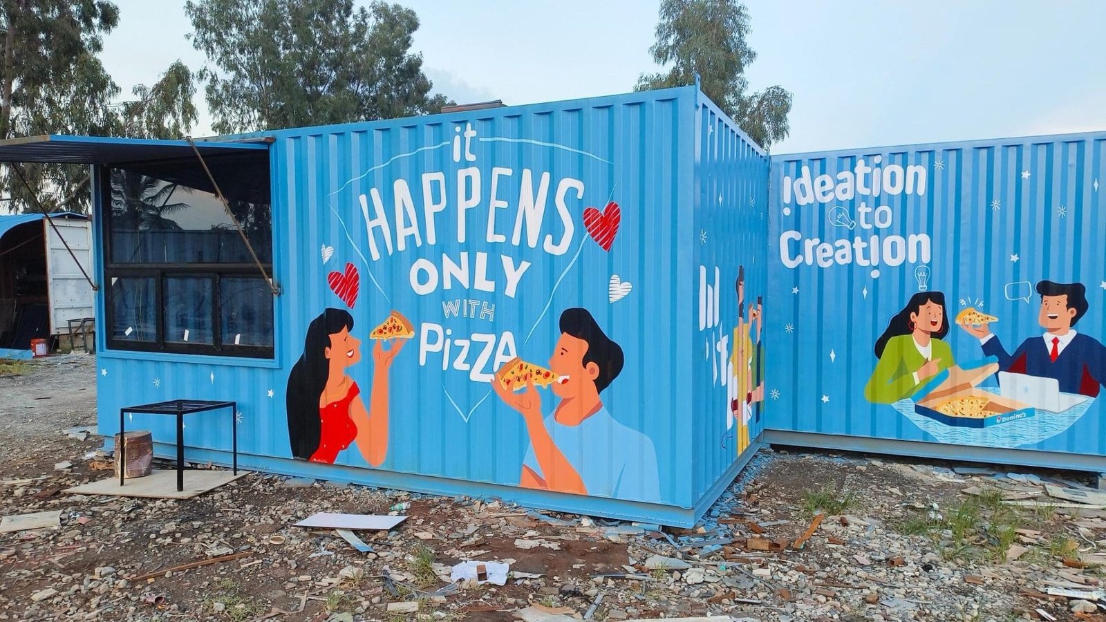 Large Blue portable cabin with multiple windows, placed on a construction site.