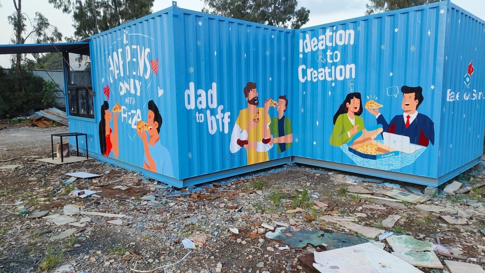 Blue portable cabins with a plain wall, positioned on a construction site.
